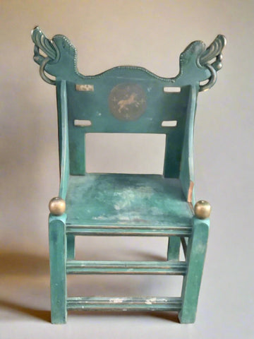 Scandinavian style teal painted chair, with a central crest and dragon/mythical creature shaped motifs.