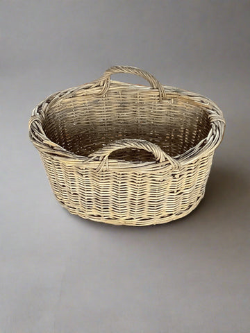 Round sturdy wicker rattan basket with double handles and wooden feet.  Designed for log storage, ideal for dressing firesides.