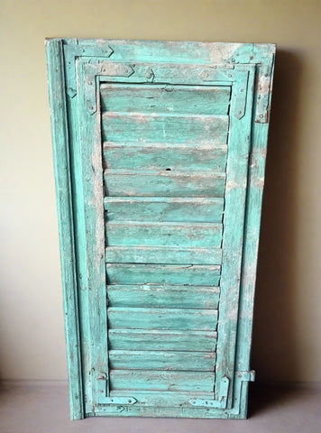 Green-painted window shutters in an aged condition.