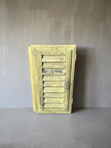 Small yellow painted window shutters, in an aged condition.