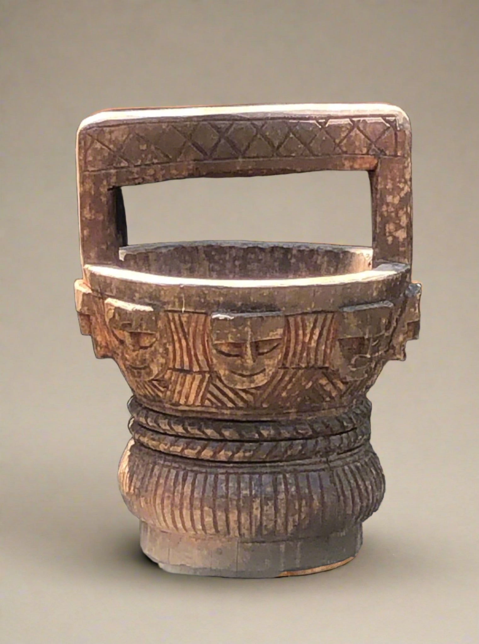 Primitive hand-carved wooden water carrier or pot with carved face features.
