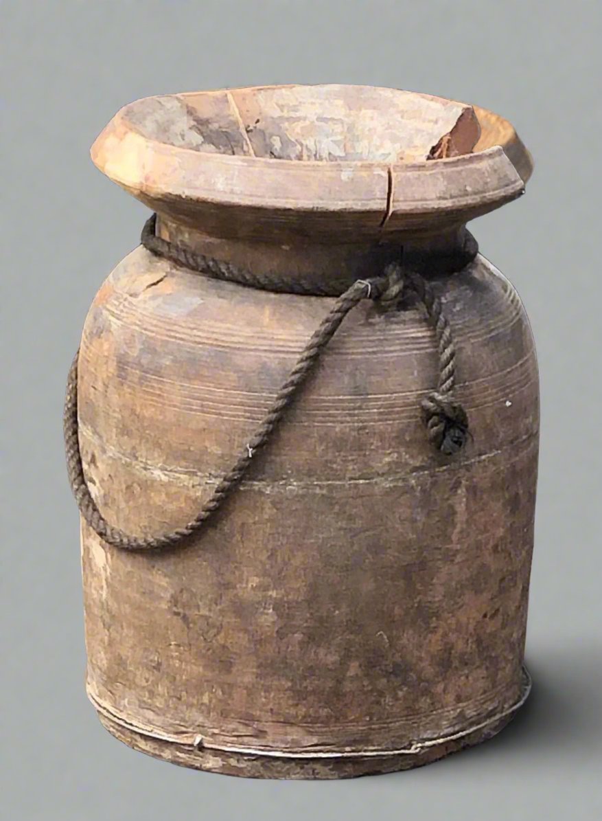 Large aged wooden vase or water carrier with rope handle and chipped lip.