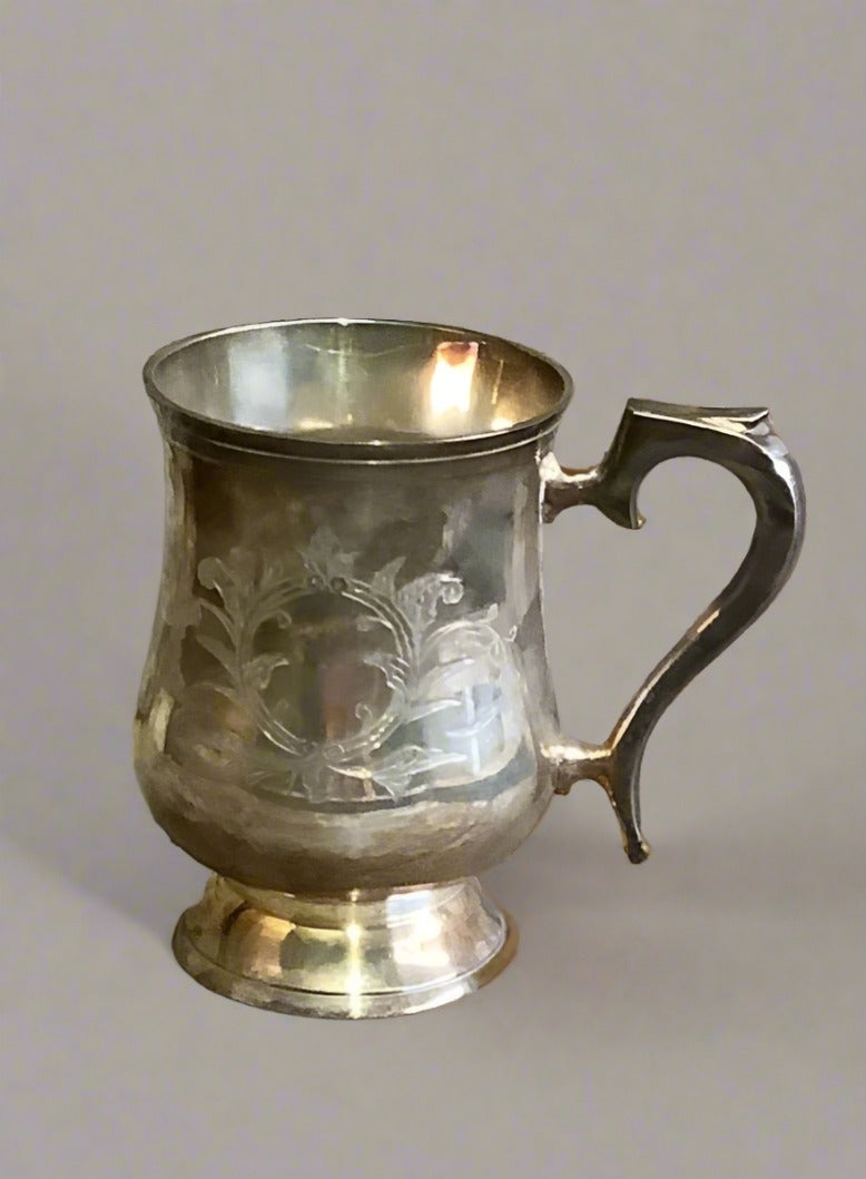 Small engraved silver tankard; Georgian style due to its curved body and large ornate curved handle. Circular engraved design on the body