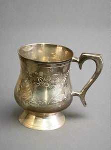 Engraved silver tankard; Georgian style due to its curved body and large ornate curved handle.