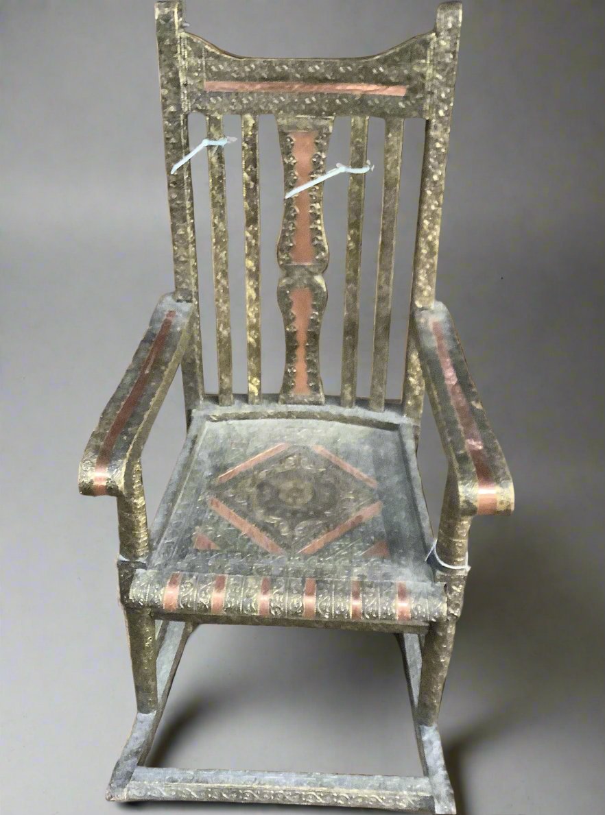 Green and gold rocking chair, cast with an intricate pattern and inlaid with bronze strips.