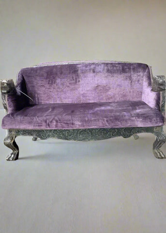 Purple velvet corduroy sofa with Victorian-style carved floral detailing to the frame and carved animal head details on the armrest.