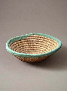 Woven basket bowl with green fabric trim.