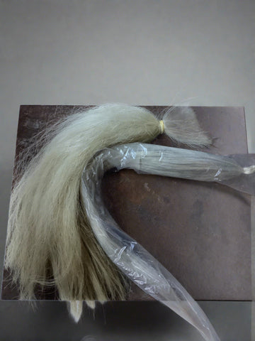 A cutting from a white horse's tail, bound with an elastic band.