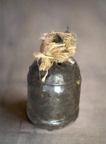 A round bell-shaped metal cowbell topped with hessian.