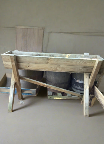 Freestanding wooden trough on high legs.