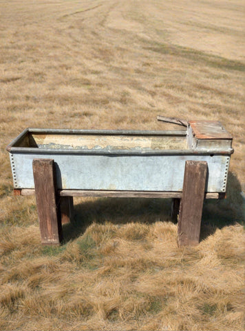 Studded rectangular metal trough on sturdy wooden legs.