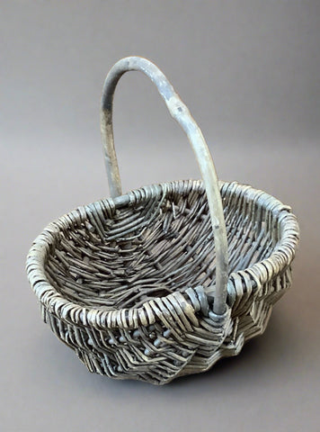 Small oblong wicker basket with carrying handle.