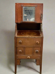 Victorian wooden wash stand with a hinged top and mirror and several drawers for storage.