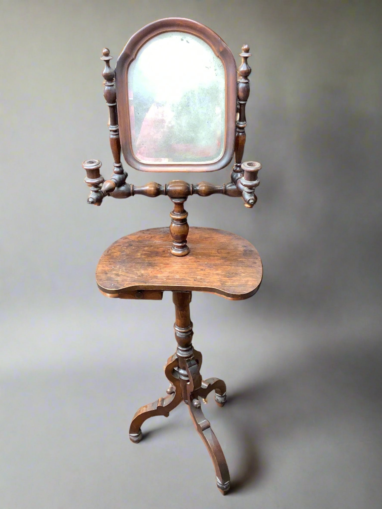 Antique wooden vanity table with two candle holders, a tiny drawer, and a mirror.