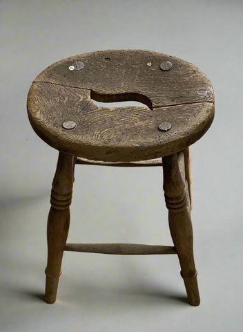 Small circular wooden stool with a carrying hole in the seat.