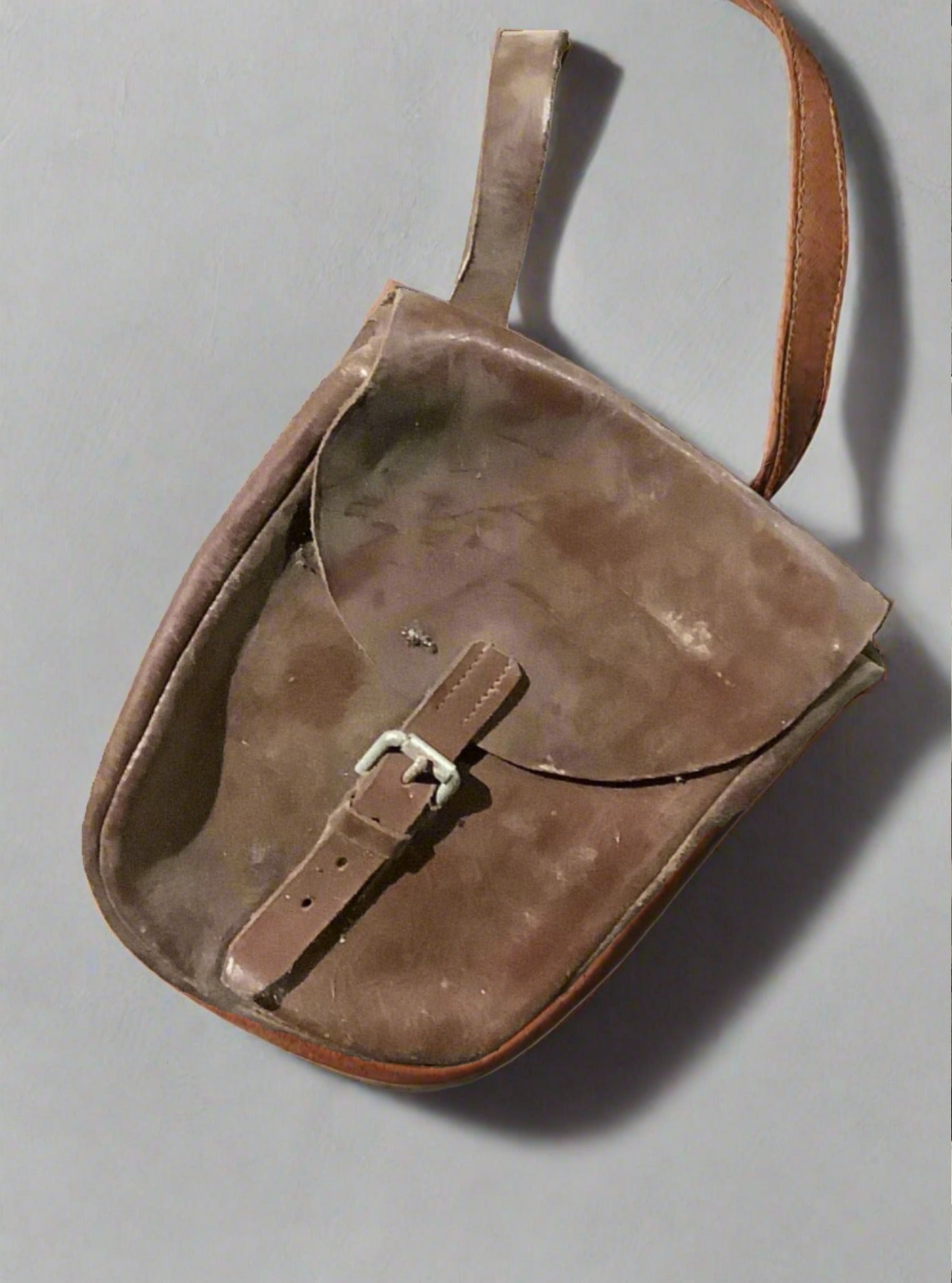 Small leather saddle bag with a buckled close and carrying strap.