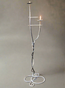 Large floor-standing metal candelabra with a modern twisted metal design and two candle sconces.