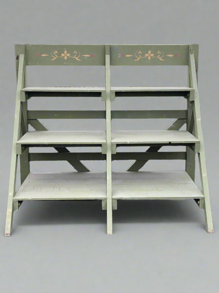 Large green display stall with three tiers and a stenciled floral motif.