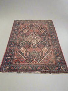 Large traditional floral rug woven with red, blue, and cream thread in geometric patterns.