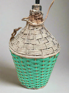 Corked glass bottle wrapped in dried reeds and green woven wicker.