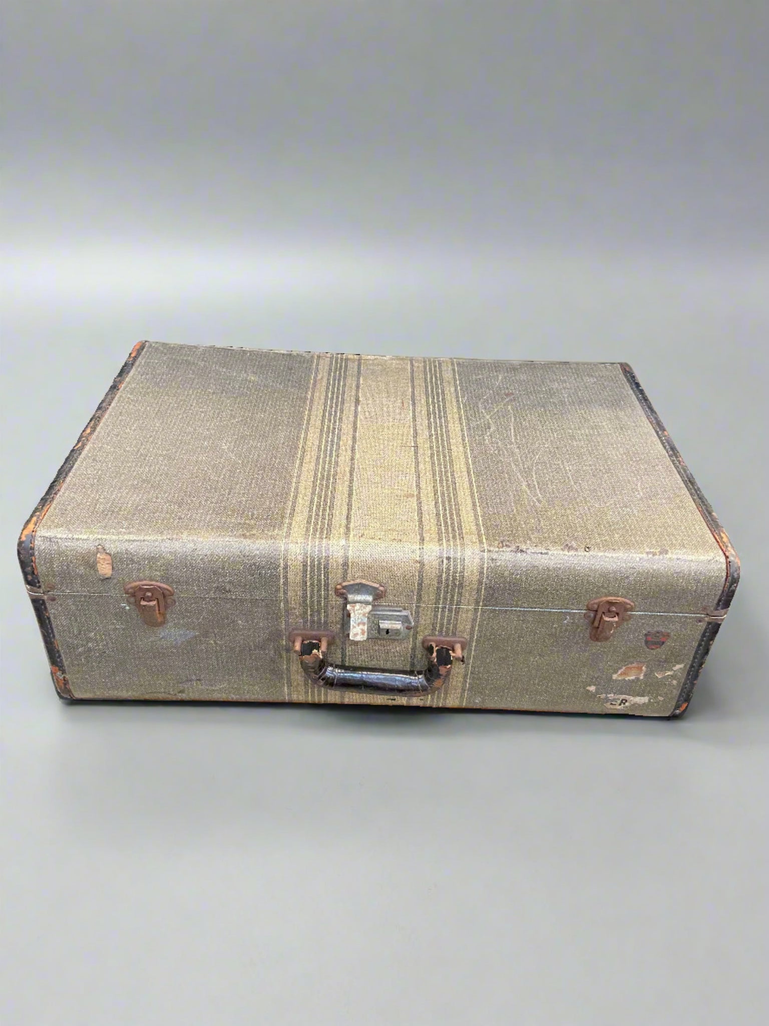 1940s style cream and grey striped suitcase with a shiny black handle.