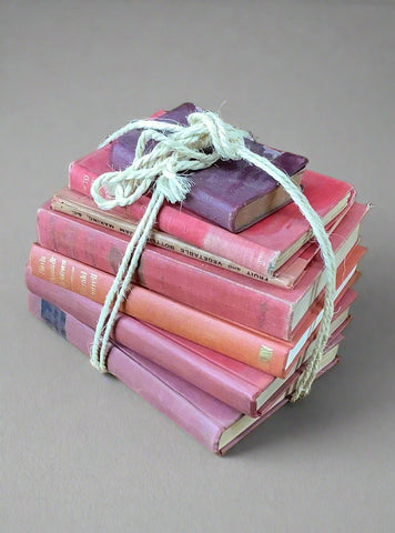 Stack of traditional hardback red and purple books, bound in jute string.