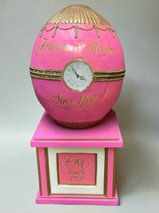 Fortnum and Mason pink egg-shaped clock cake, sitting on a plinth.