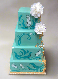 Four-tier teal faux celebration cake with flower decorations and gold detailing.