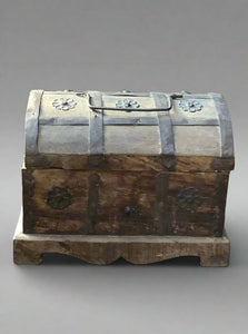 Traditional wooden chest decorated with metal flowers and handle.