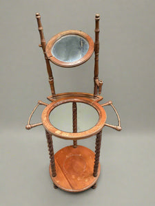 Antique wooden vanity washstand with an oval mirror and frame for a sink bowl. There are candle holders on either side of the mirror.