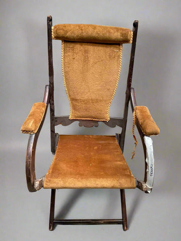 Wooden folding chair upholstered with camel brown chenille fabric.