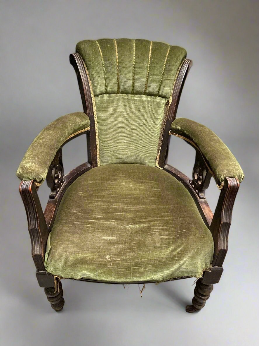 Antique green armchair with detailed wooden frame.