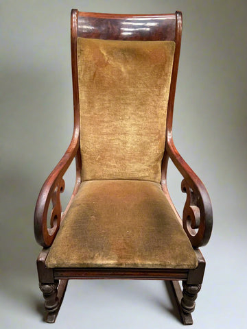 Tall solid wood rocking chair with worn, ocre fabric padding.