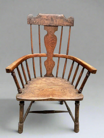 Antique carved wooden Windsor armchair with H stretcher and slatted back support.