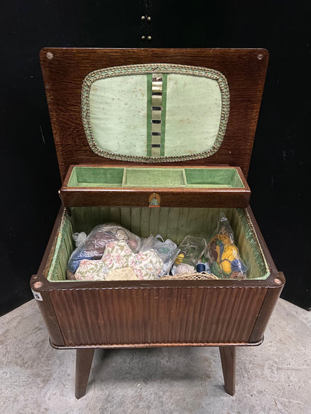 1960's style wooden storage unit on legs with a mint green fabric lining. The unit contains haberdashery smalls Film TV Props London