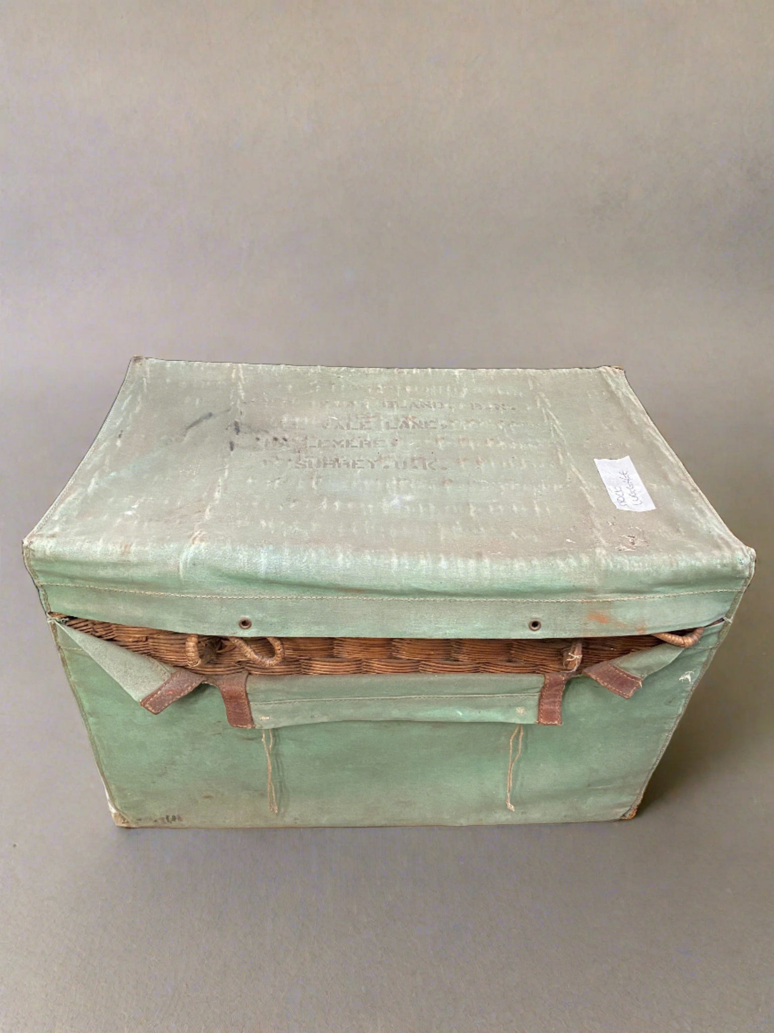 Large wicker trunk with a mint green fabric and leather cover.