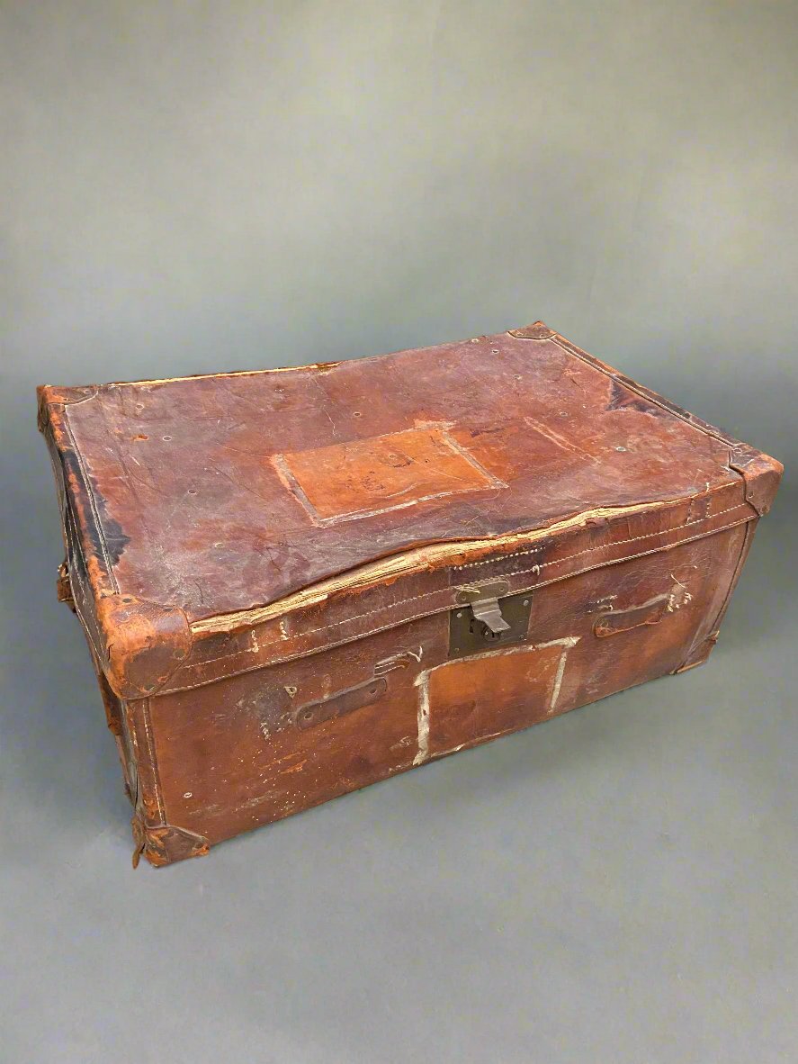 Large travelling trunk made from vibrant red/orange coloured leather in a heavily aged condition.