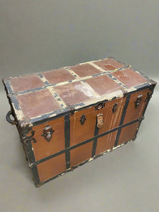 Large brown and black gridded steamer trunk with metal medieval-style hardware.