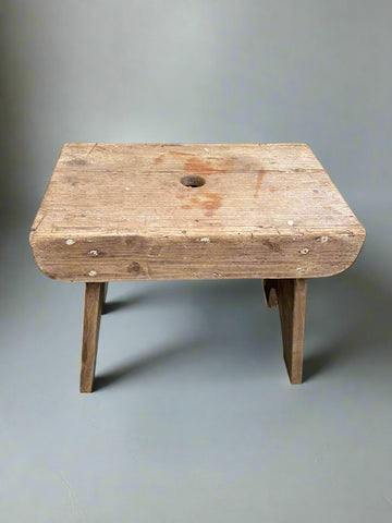 Small rectangular child's wooden stool with tiny central hole.