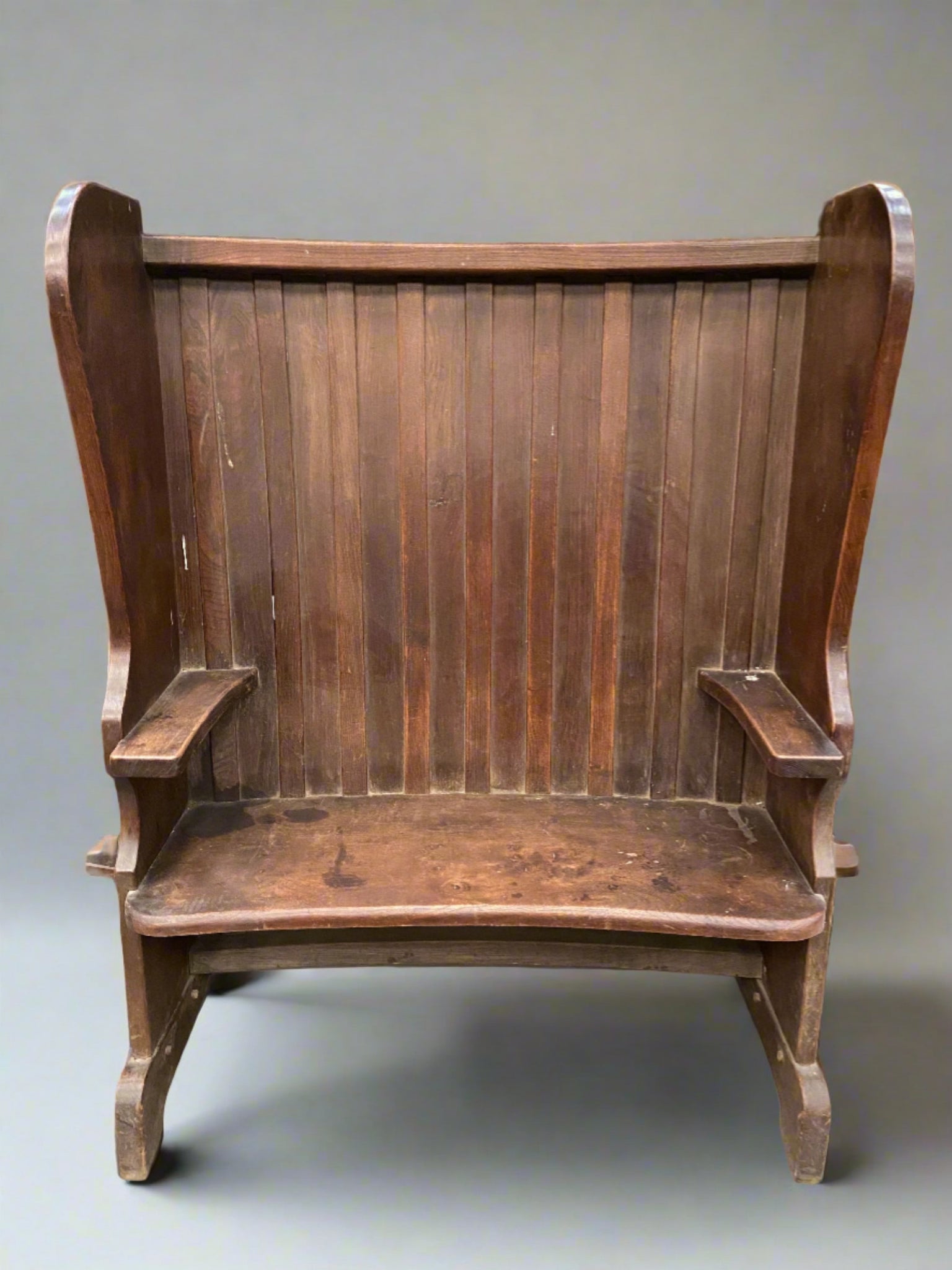 High back two seater antique wooden bench. A typical form found in taverns and farmhouses and designed for the fireside. The high back and backboards kept the occupants cosy and draught free.