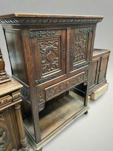 Arts and crafts hand-carved wooden cabinet with a traditional foliage design on the double doors and wrought iron hardware.