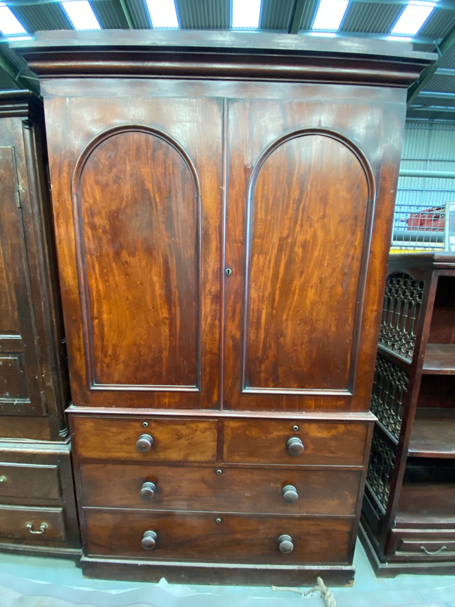 Large wooden wardrobe with arch detailing in the double doors and four drawers.