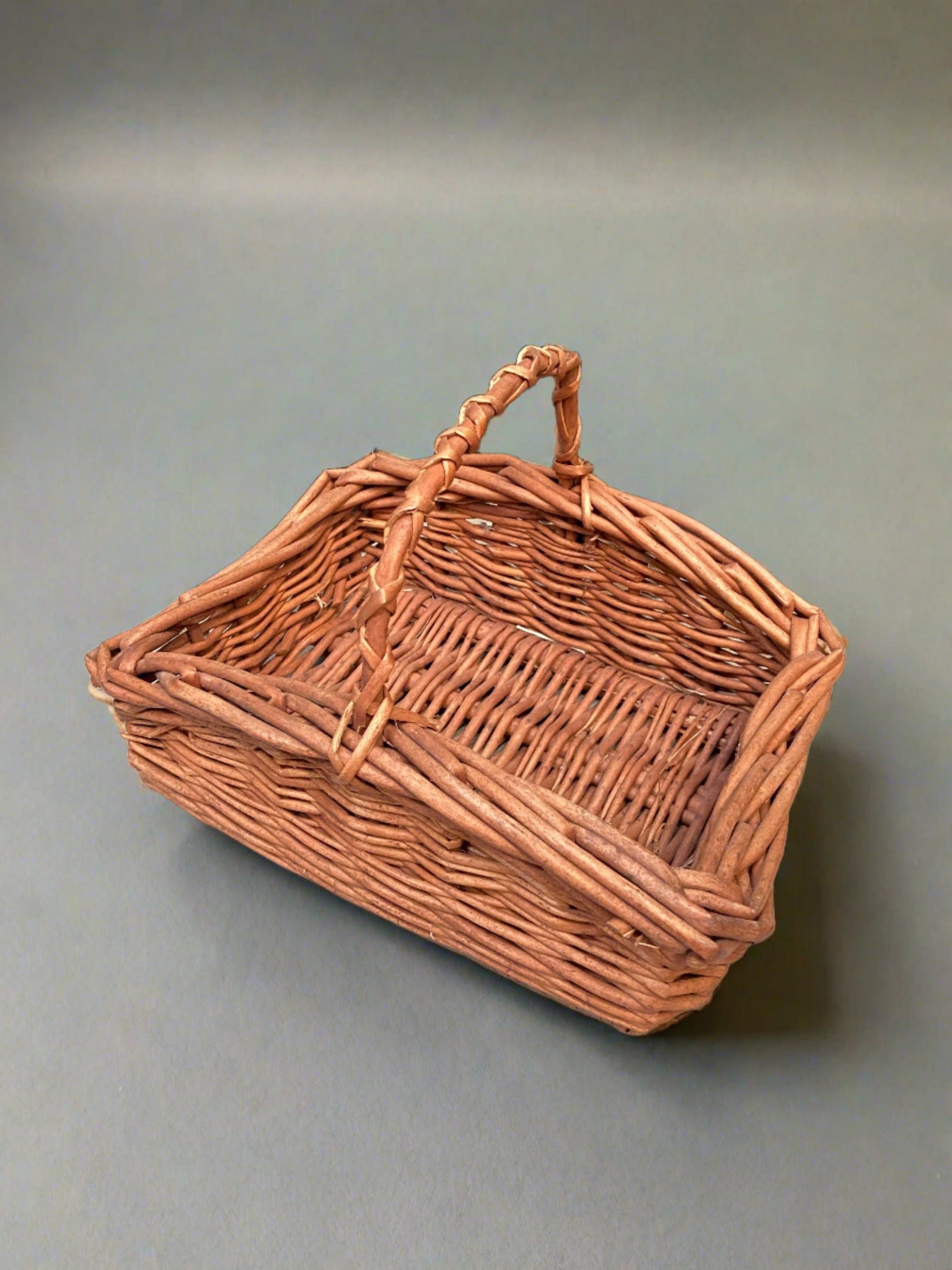 Square stained wicker basket with a criss cross handle.