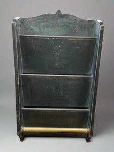 Black magazine rack with a brass bar. Circa 1895.

You would often see these in barbershops and coffee houses, with the brass bar holding a rag for a barman or newspapers.