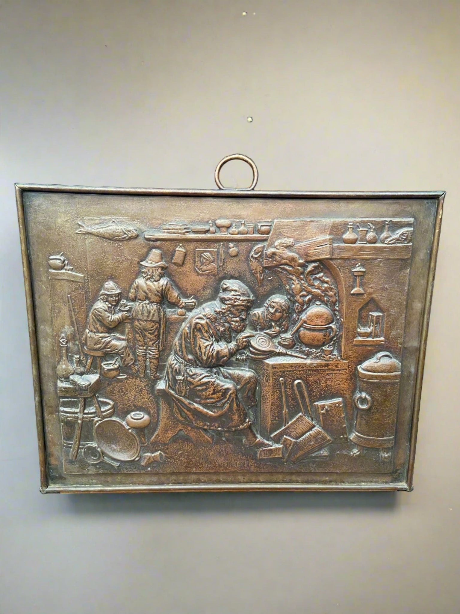 Antique hanging repousse plaque featuring a pictorial workshop scene.