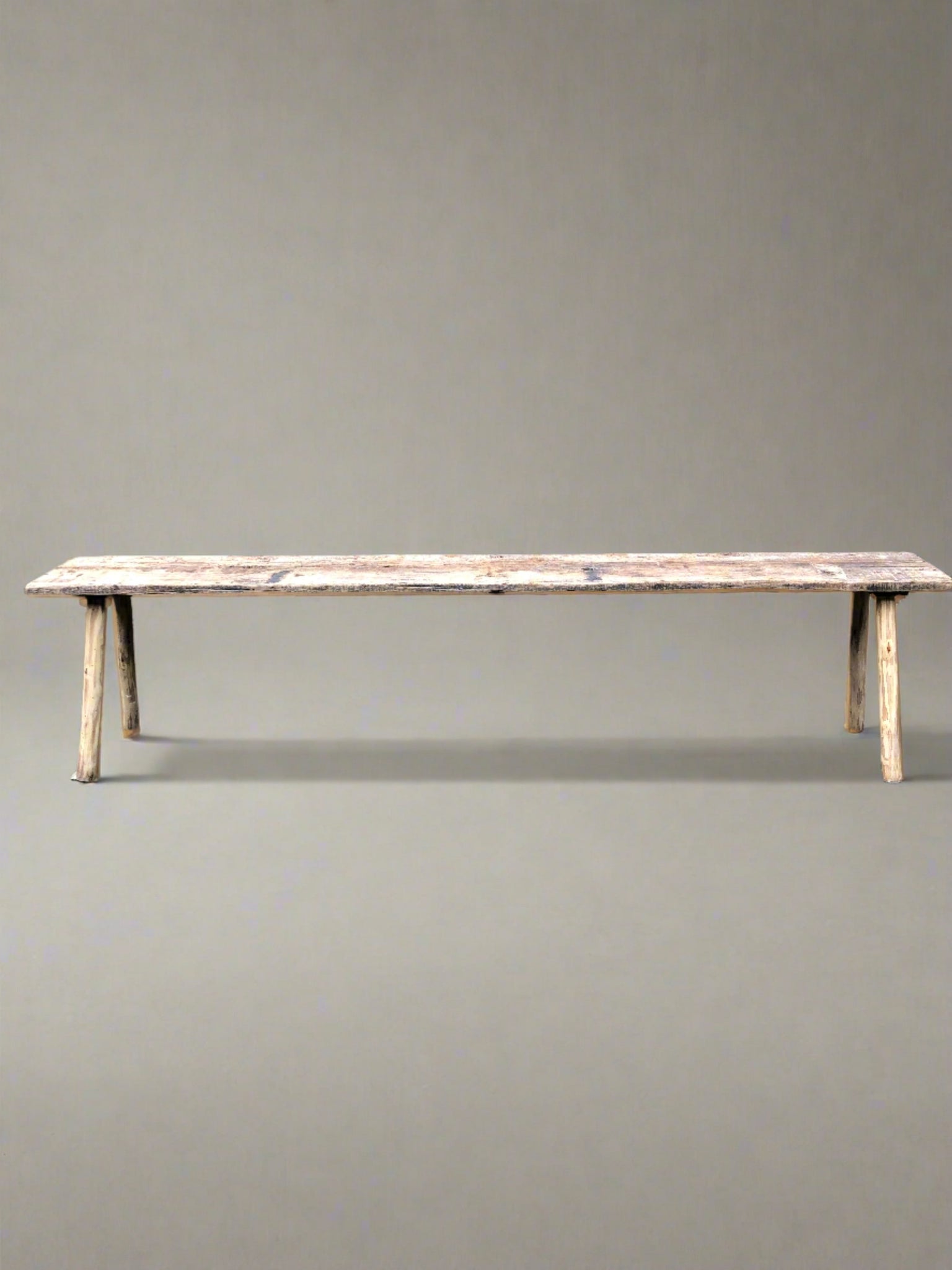 Long and narrow rustic wooden bench.