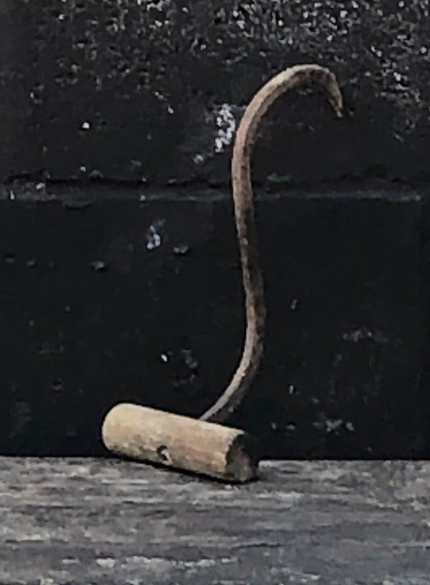 Rustic&nbsp;hay bale hook with wooden handle and metal hook.
