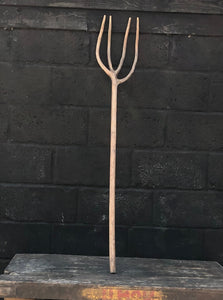 Rustic hay fork with wooden handle and metal prongs.