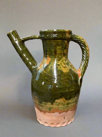 Tall earthenware jug with mottled green gloss glazing, ribbed design, spout and handle.