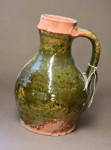 Tall earthenware walnut oil jar with mottled green gloss glazing and handle (missing cork.)